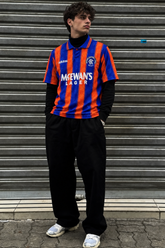 Model wearing Rangers 1993-94 blue and orange McEwan's Lager away shirt in gritty streetwear styling