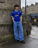Model wearing Rangers 2005-06 blue Carling home shirt in gritty Glasgow street setting